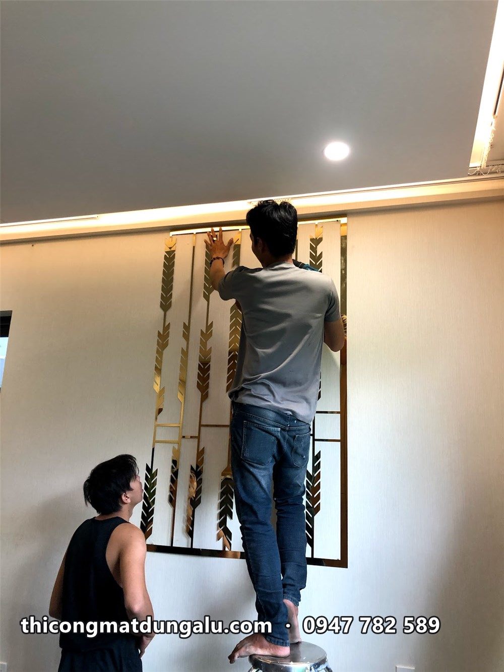 Hai thợ đứng trên thang lắp vách bông lúa lên tường